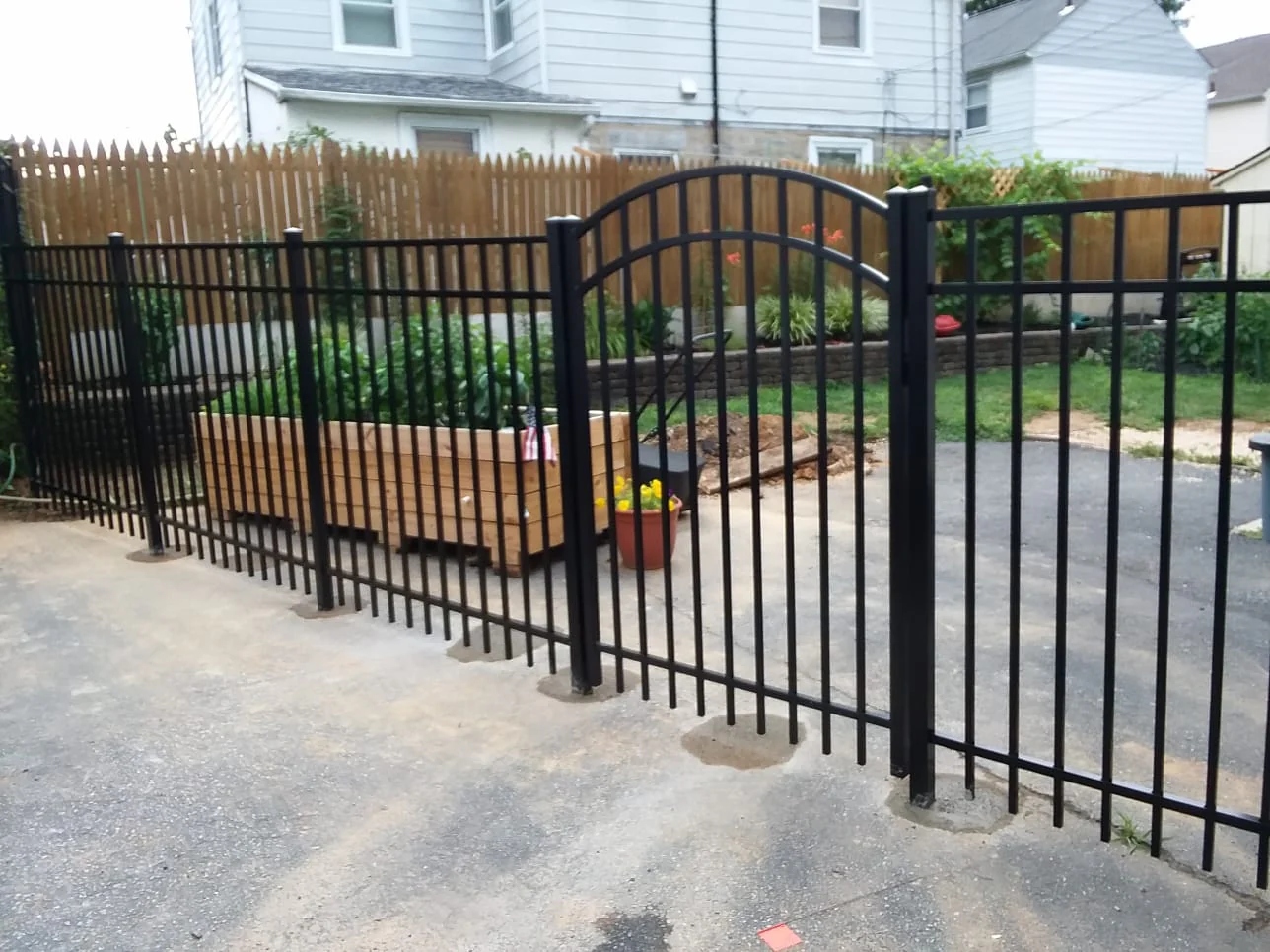 Black aluminum fence with arched walk gate, fresh concrete post footings