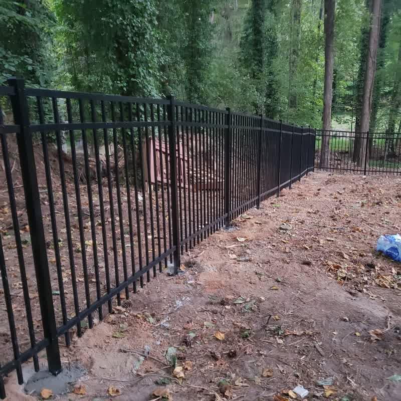 Black aluminum fence installation in progress along a wooded property line in Triangle NC