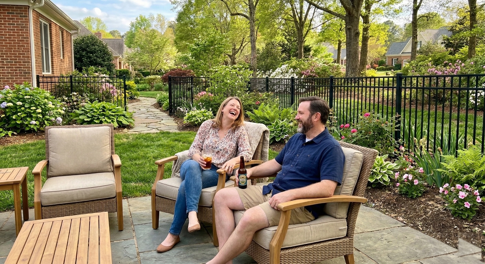 Couple laughing on a patio surrounded by black aluminum aluminum fence and garden