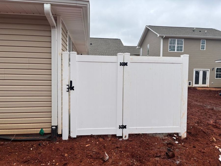 White vinyl privacy fence double gate installation on red clay NC soil