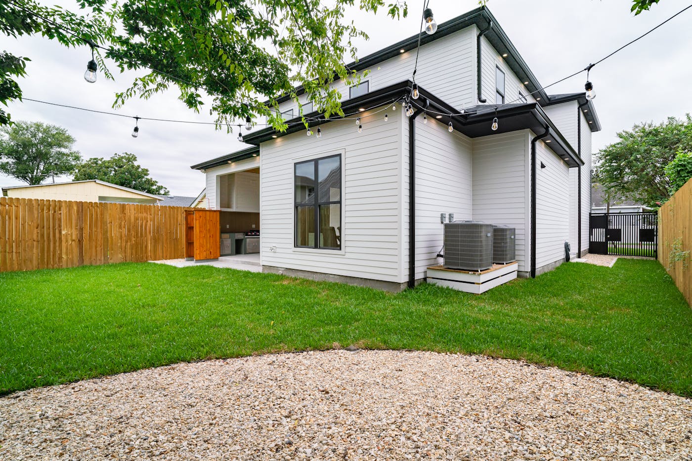 Residential backyard fully enclosed by a new wood privacy fence with string lights