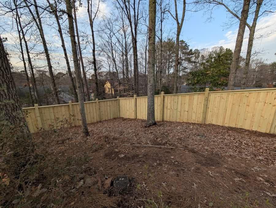 Cap and trim wood privacy fence wrapping a wooded lot in North Carolina