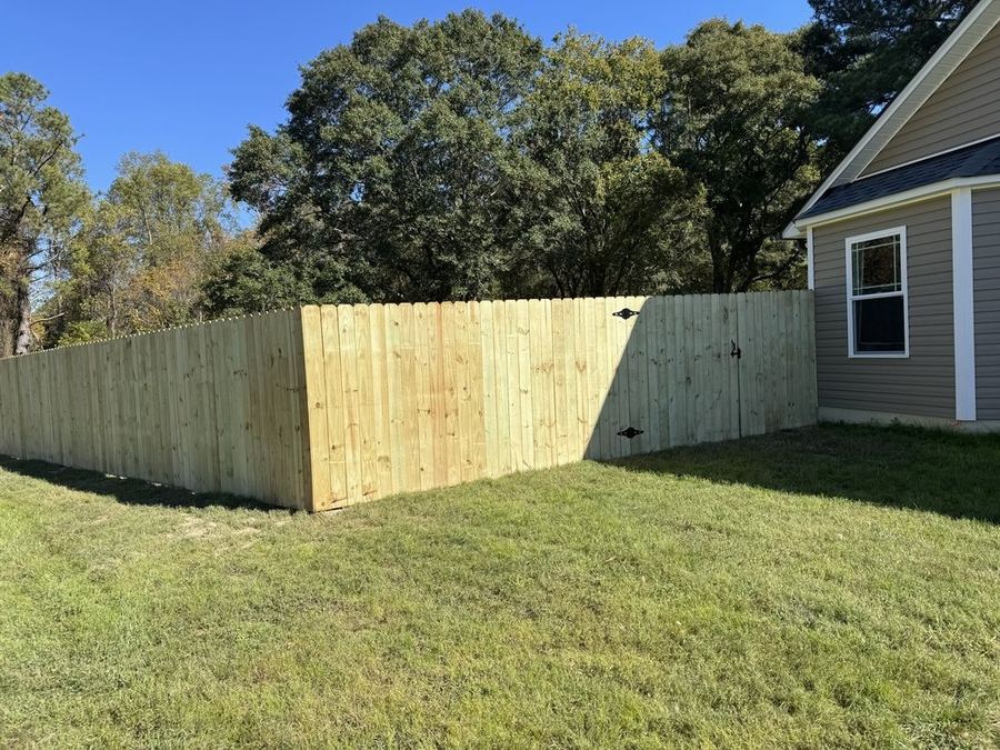 Pressure-treated dog-ear fence along property