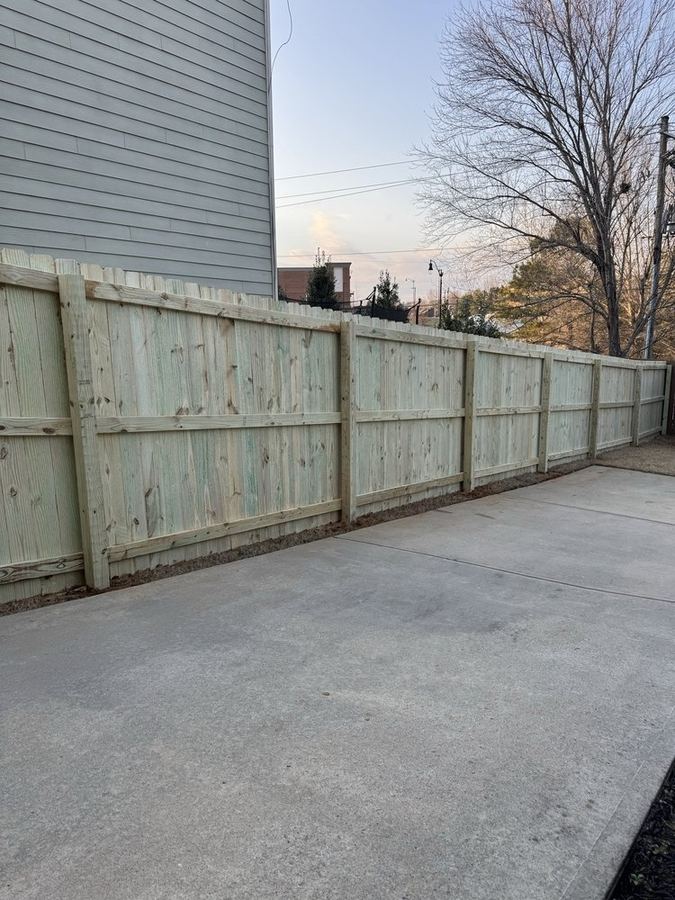 Fresh pressure-treated dog-ear wood privacy fence installation in North Carolina