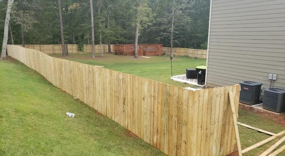 Long run of pressure-treated dog ear wood privacy fence fully enclosing a Triangle NC backyard
