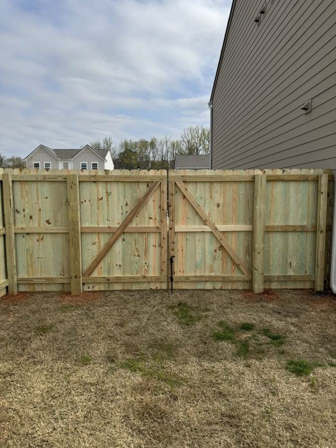 New pressure-treated wood privacy fence with double drive gate in a Triangle NC backyard