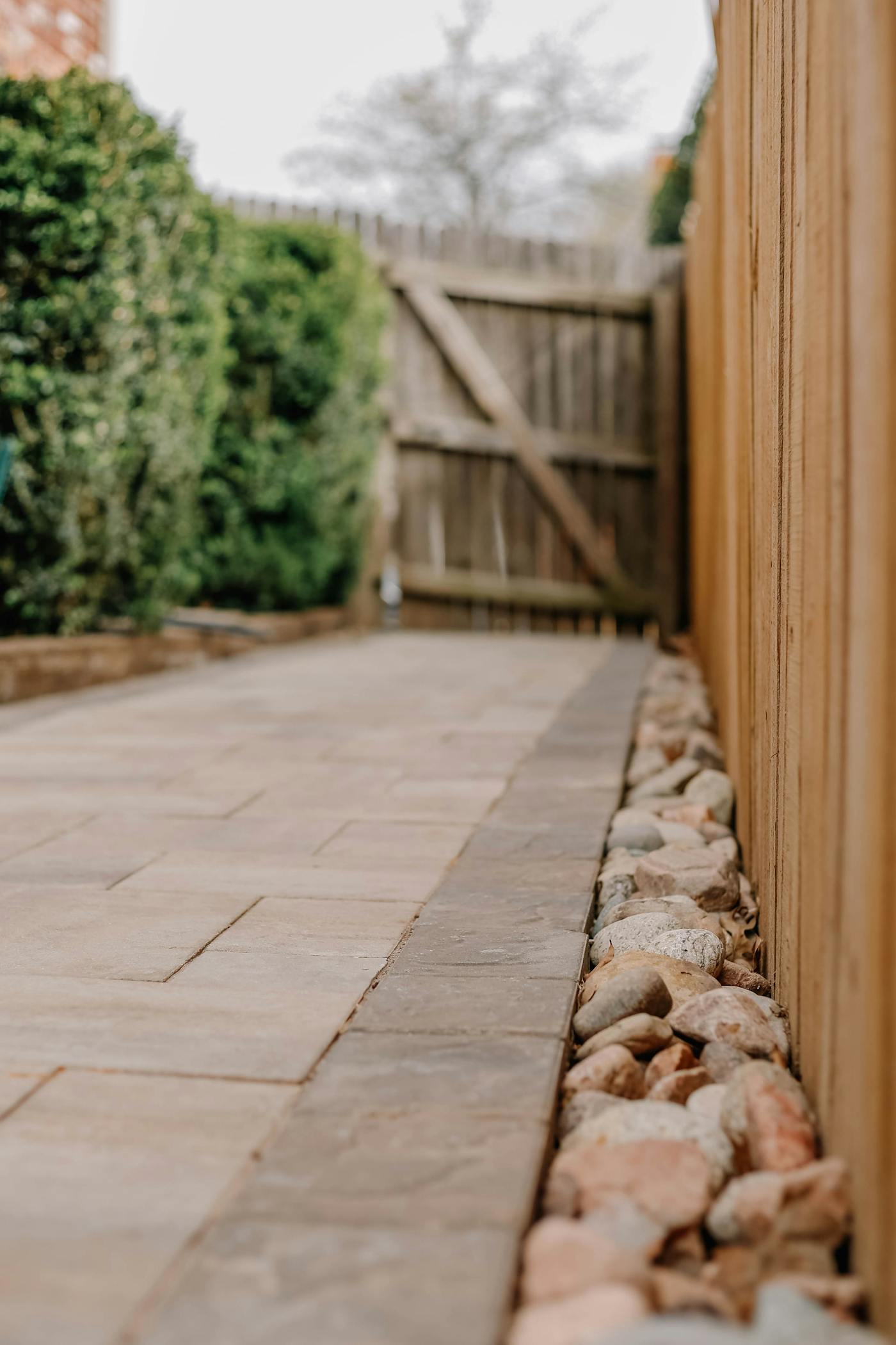 Tall wood privacy fence running alongside a backyard stone path
