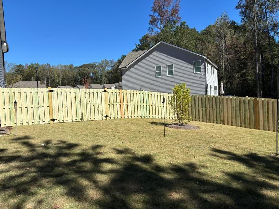 Shadow box wood privacy fence in a Triangle NC neighborhood with clear blue sky